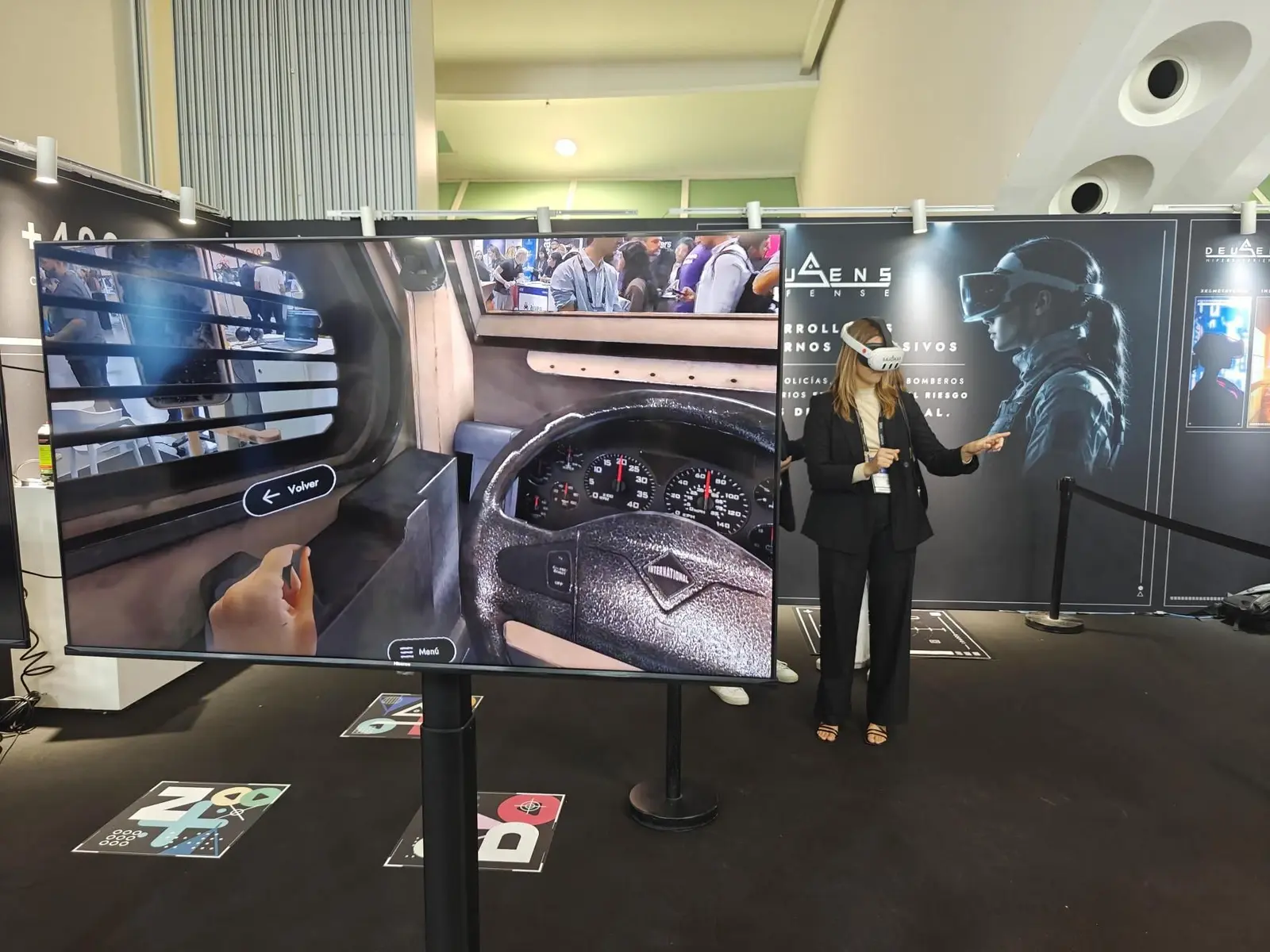 Visitante con gafas Meta Quest 3 junto a una pantalla que muestra la vista del conductor del vehículo